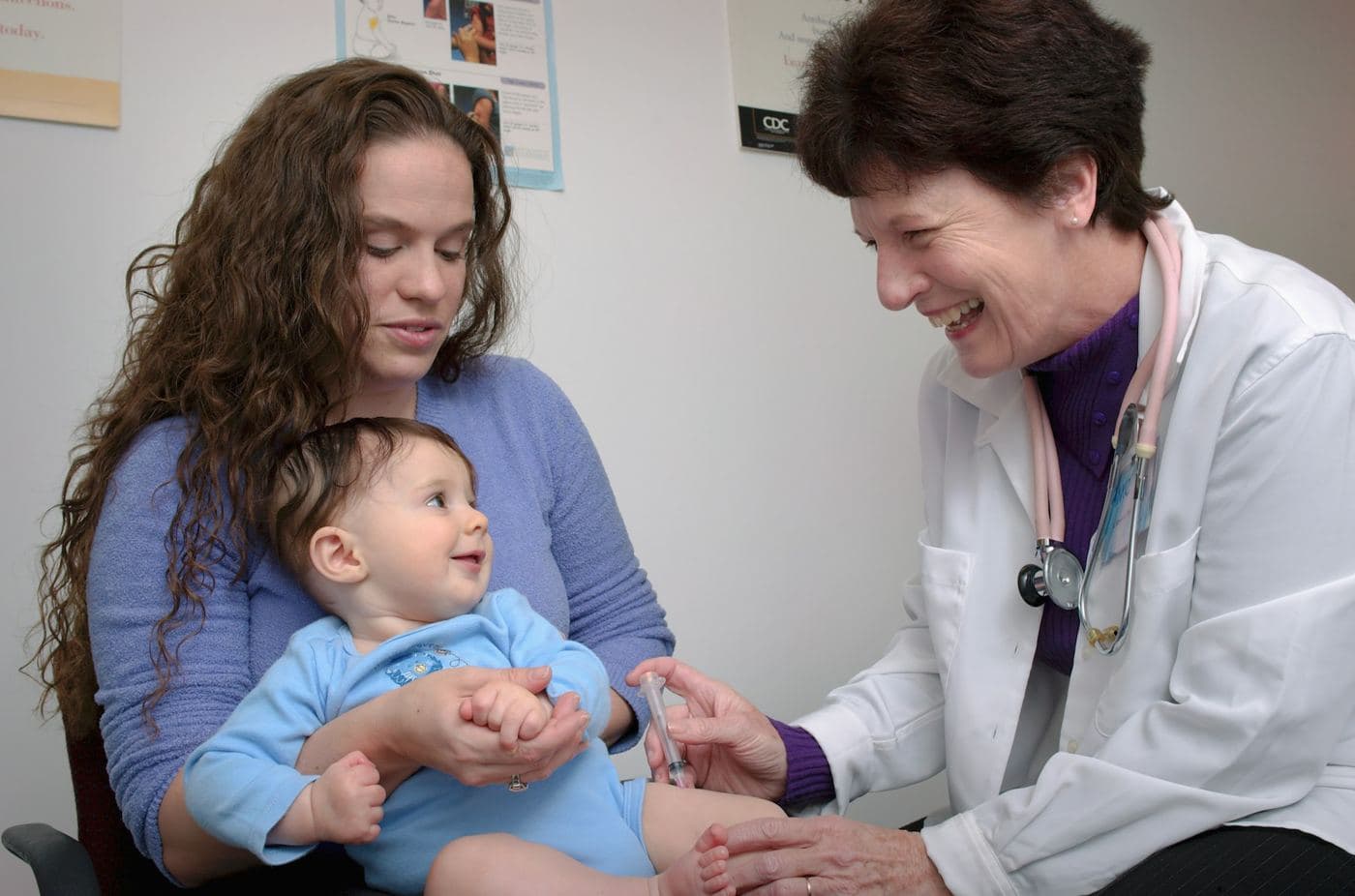 A doctor examining a baby sitting on his mother's lap