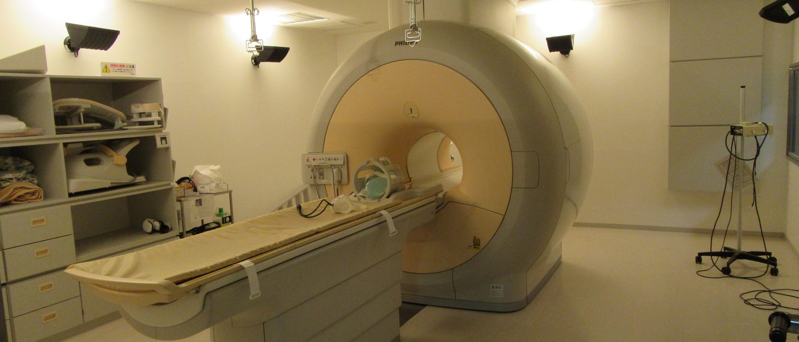 An MRI scanner with its patient table and head coil in a quiet scan room.